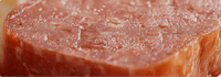 Close-up of a piece of raw meat with a textured surface.